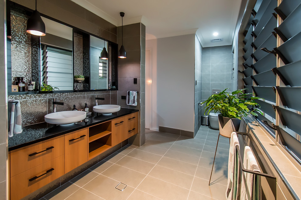 Bathroom - mid-sized modern master brown tile and ceramic tile ceramic tile, brown floor and double-sink bathroom idea in Other with flat-panel cabinets, medium tone wood cabinets, a wall-mount toilet, brown walls, a vessel sink, granite countertops, black countertops, a niche and a floating vanity