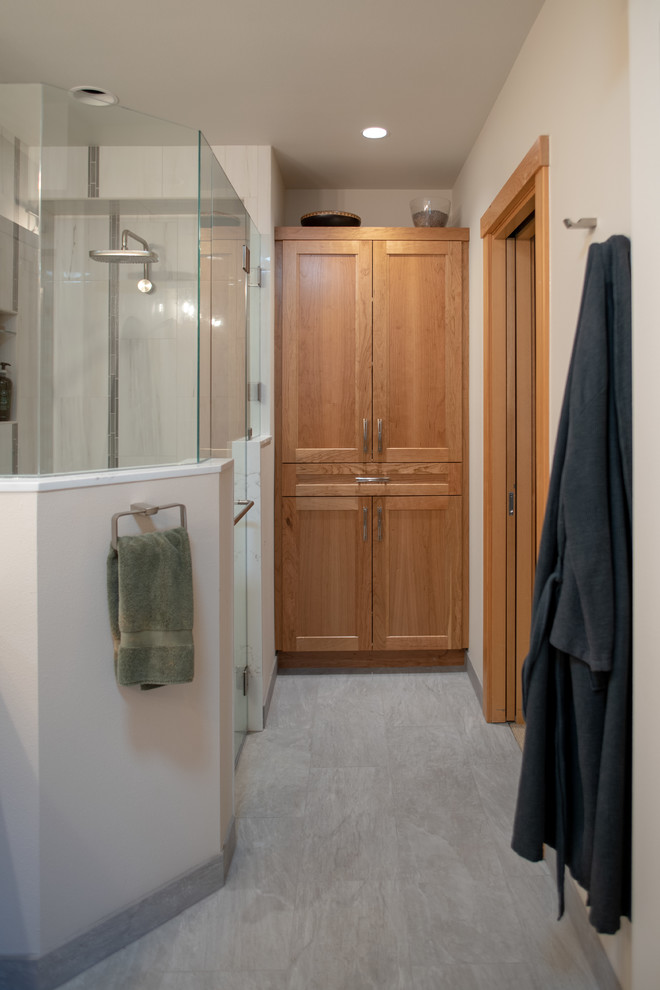 This is an example of a medium sized traditional ensuite bathroom in Seattle with recessed-panel cabinets, medium wood cabinets, a built-in shower, a two-piece toilet, white tiles, ceramic tiles, white walls, porcelain flooring, a submerged sink, engineered stone worktops, grey floors, a hinged door, white worktops, double sinks and a built in vanity unit.