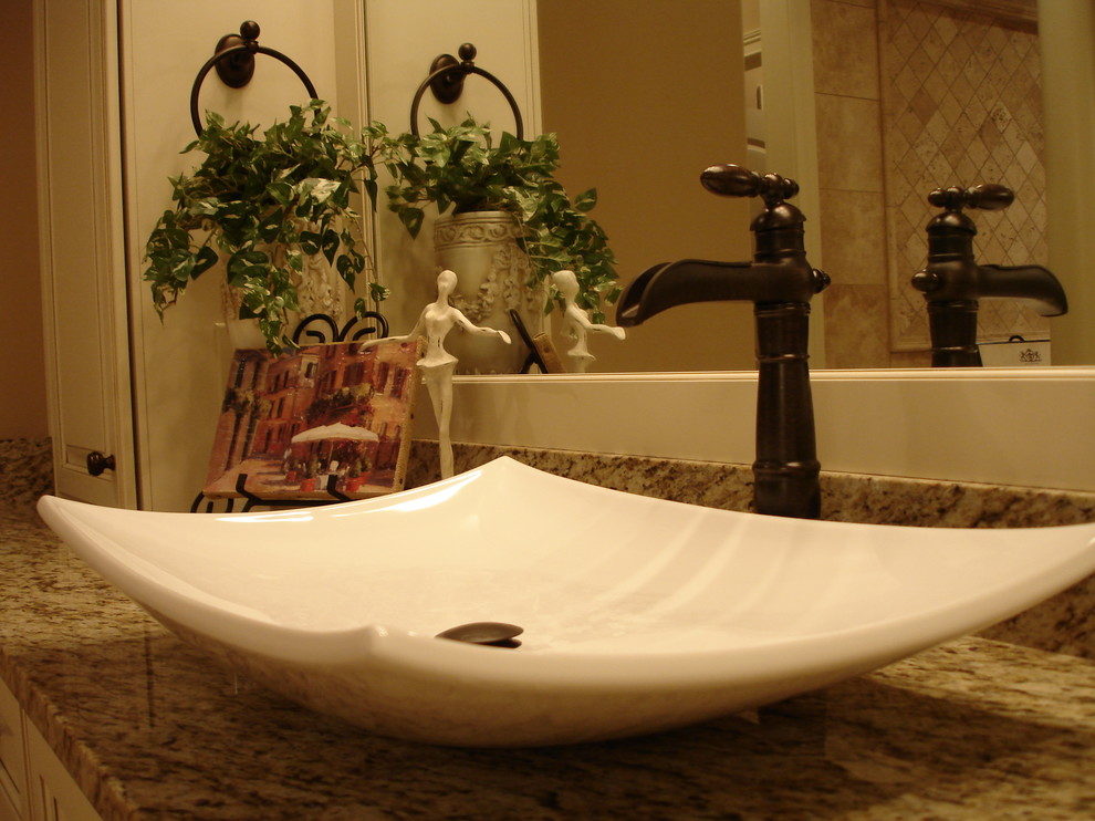 Inspiration pour une salle de bain traditionnelle avec une vasque, un placard avec porte à panneau surélevé, des portes de placard beiges, un plan de toilette en granite, un carrelage beige, un carrelage de pierre, un mur beige et un sol en travertin.