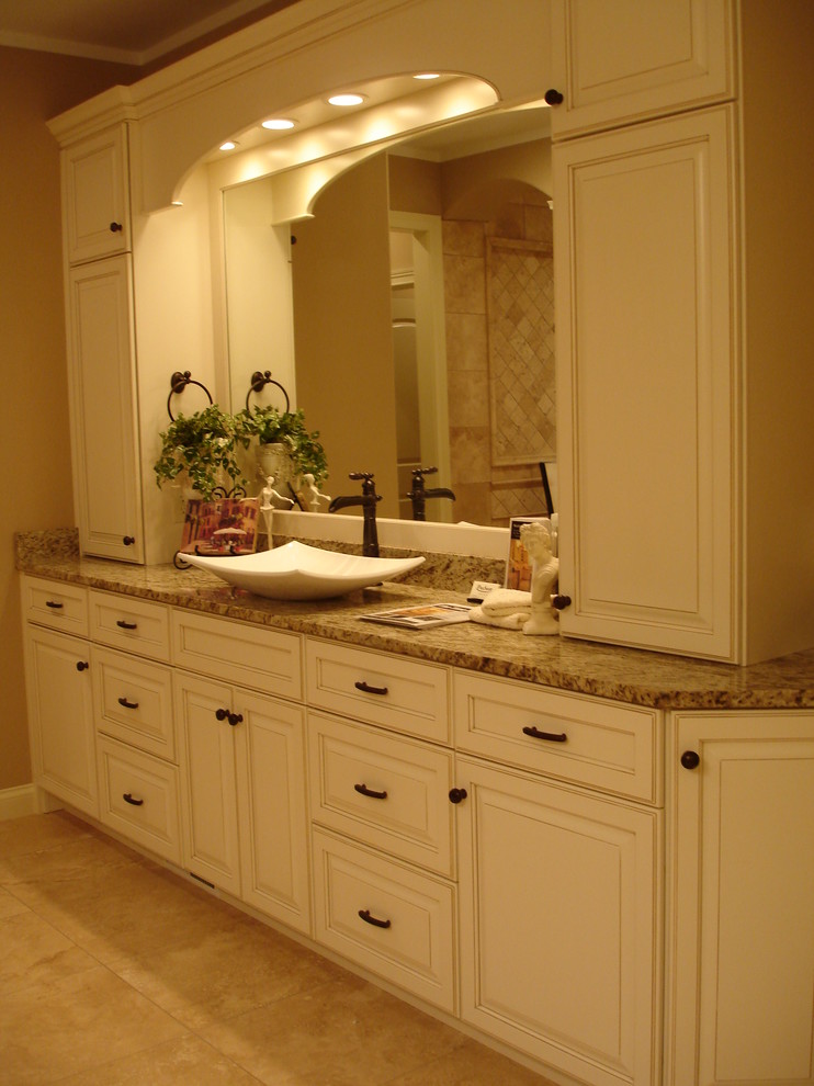 Exemple d'une grande salle de bain principale chic avec un carrelage beige, un carrelage de pierre, un mur beige, un sol en travertin, une vasque, un placard avec porte à panneau surélevé, des portes de placard beiges, un plan de toilette en granite et un sol beige.