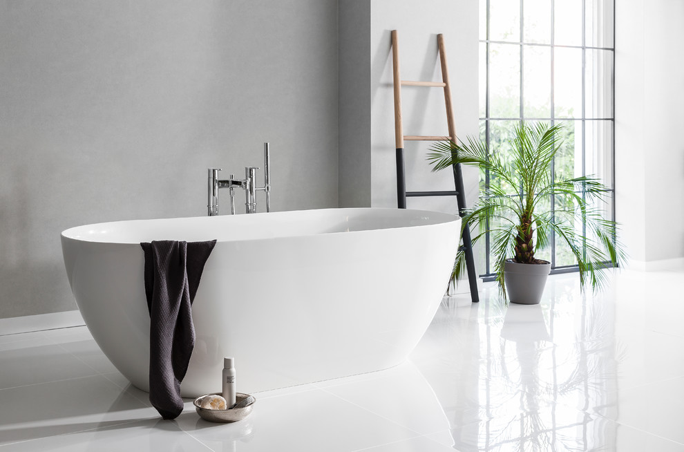 Inredning av ett modernt badrum, med ett fristående badkar, grå väggar och klinkergolv i porslin