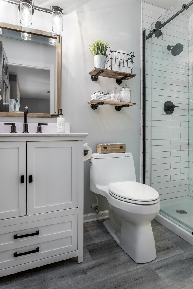Idéer för ett mellanstort lantligt en-suite badrum, med skåp i shakerstil, vita skåp, en dusch i en alkov, vit kakel, keramikplattor, grå väggar, klinkergolv i porslin, ett nedsänkt handfat, marmorbänkskiva, grått golv, dusch med skjutdörr och en toalettstol med hel cisternkåpa