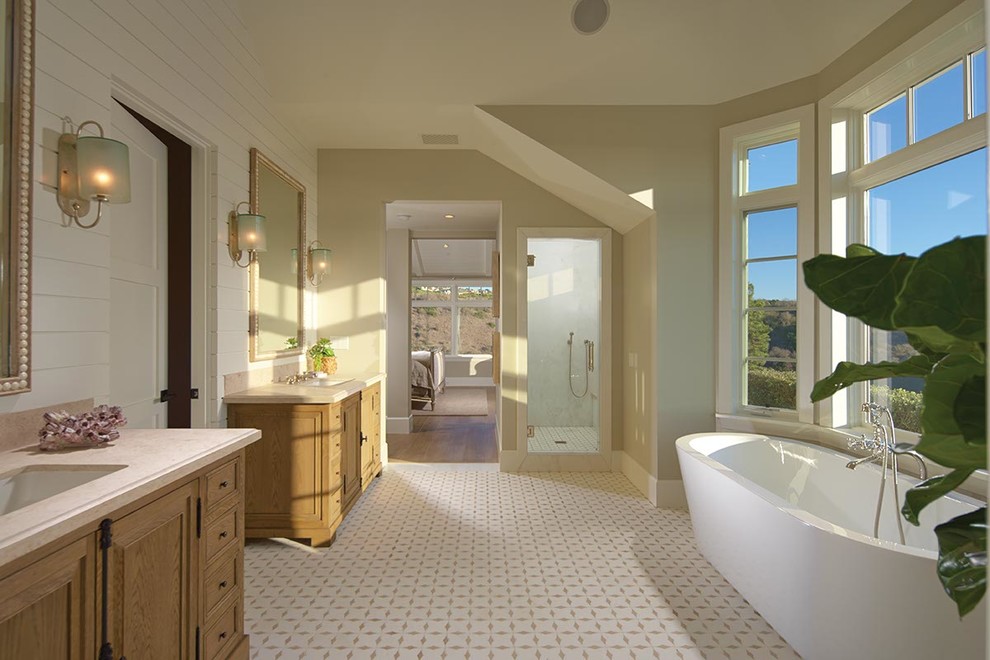 На фото: ванная комната в морском стиле с врезной раковиной, светлыми деревянными фасадами, отдельно стоящей ванной и душем в нише