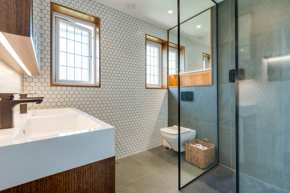 Inspiration for a medium sized modern bathroom in Hertfordshire with recessed-panel cabinets, medium wood cabinets, a wall mounted toilet, white tiles, cement tiles, white walls, slate flooring, grey floors, a console sink and an open shower.