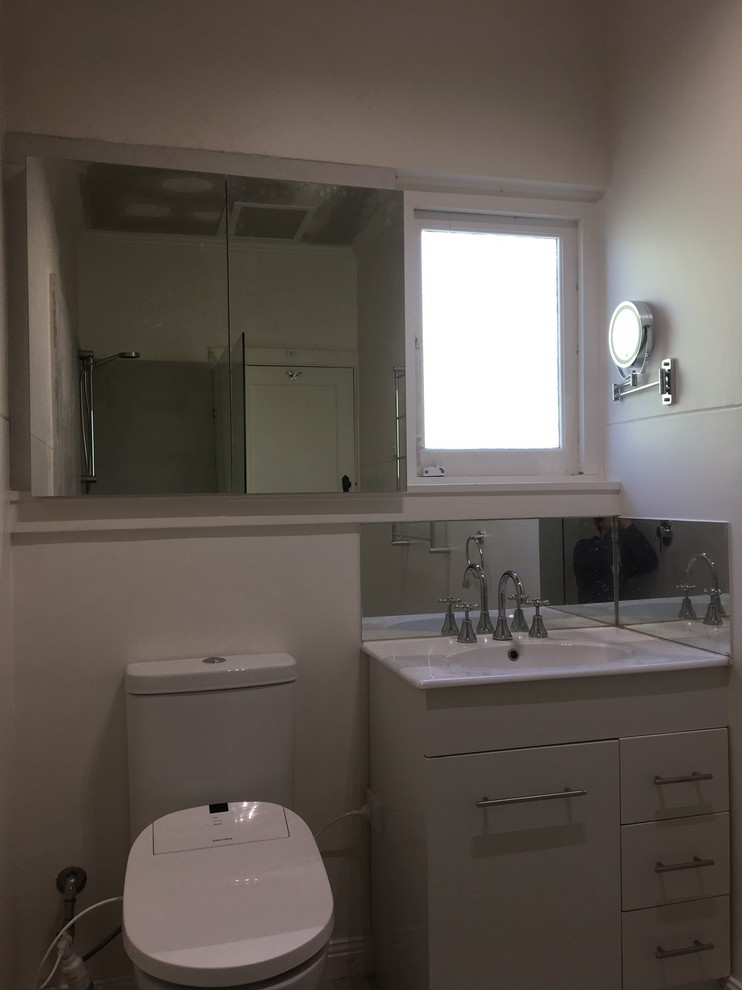 Foto di una piccola stanza da bagno minimalista con bidè, ante lisce, ante bianche, doccia ad angolo, piastrelle bianche, piastrelle in ceramica, lavabo integrato, top in vetro, top bianco e doccia aperta