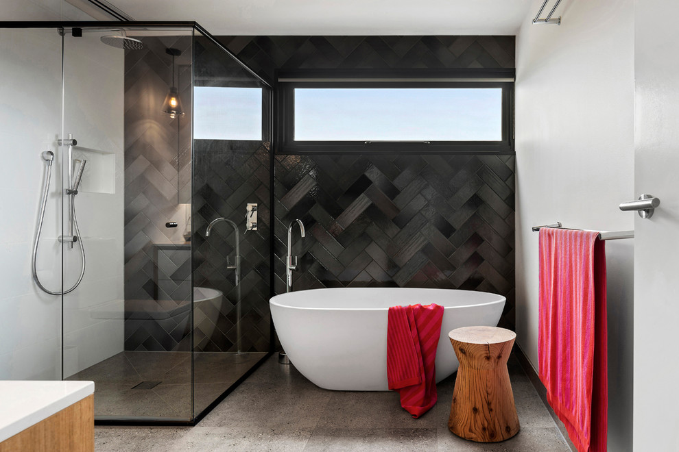Пример оригинального дизайна: ванная комната среднего размера в современном стиле с отдельно стоящей ванной, угловым душем, черной плиткой, серыми стенами, серым полом и душем с распашными дверями