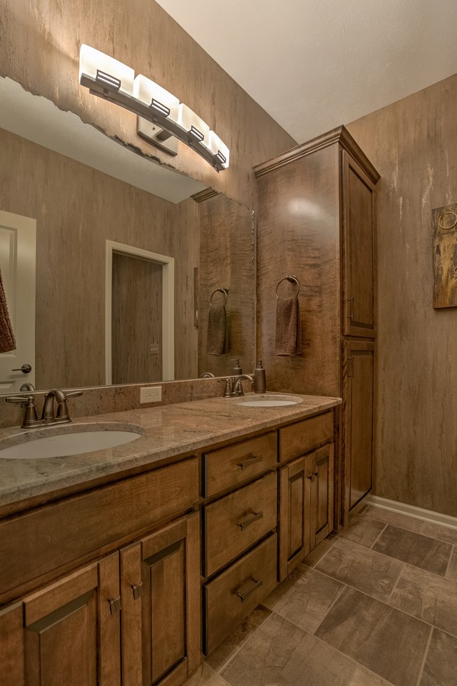 Inspiration for a large traditional shower room bathroom in Omaha with raised-panel cabinets, medium wood cabinets, brown walls, porcelain flooring, a submerged sink, granite worktops and grey floors.
