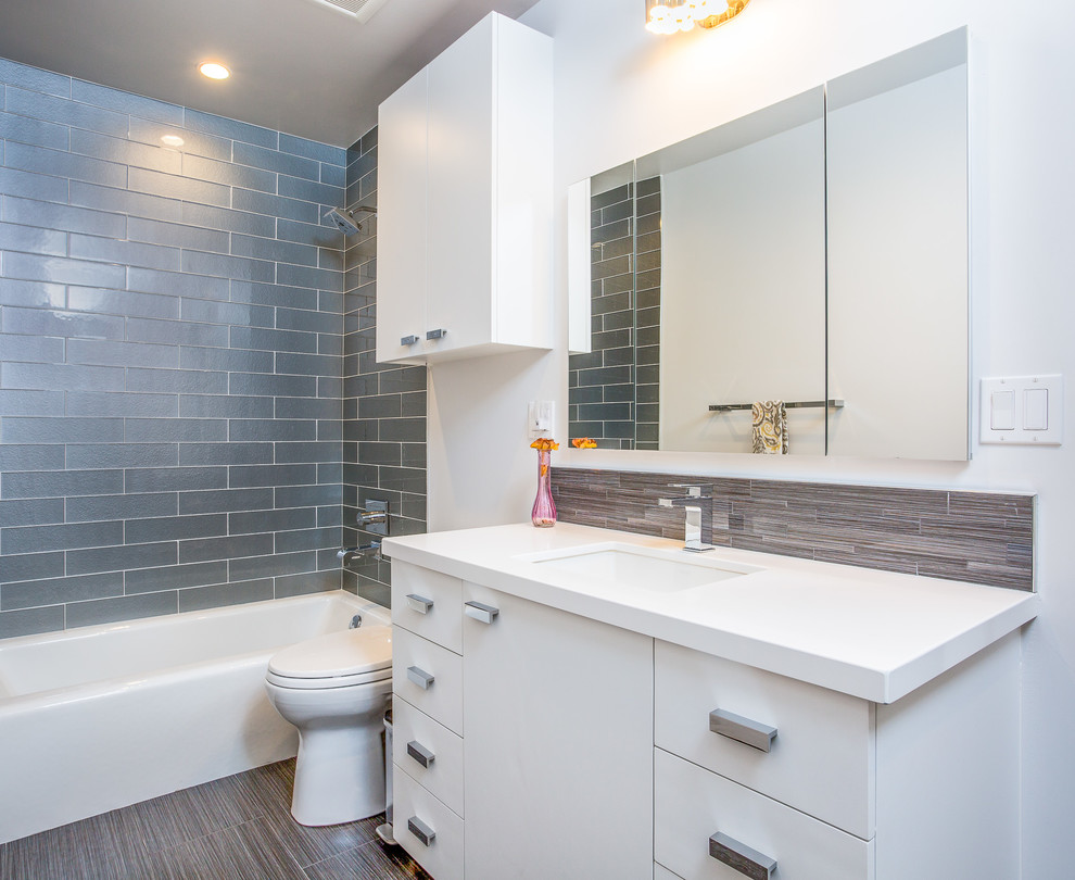 Photo of a medium sized modern family bathroom in Orange County with flat-panel cabinets, white cabinets, an alcove bath, a one-piece toilet, grey tiles, porcelain tiles, porcelain flooring, a submerged sink, engineered stone worktops, an alcove shower, white walls, brown floors, a shower curtain and white worktops.
