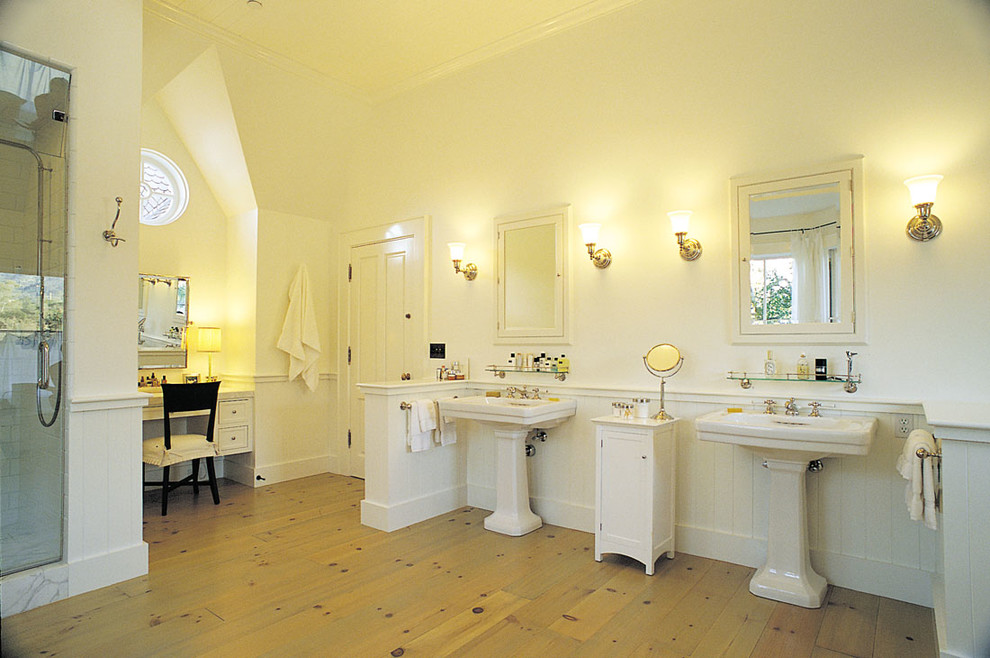 Ejemplo de cuarto de baño principal campestre grande con puertas de armario blancas, bañera exenta, ducha empotrada, paredes blancas, suelo de madera clara, lavabo con pedestal y baldosas y/o azulejos blancos