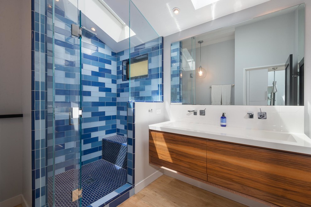 Foto di una stanza da bagno con doccia contemporanea con ante lisce, ante in legno scuro, doccia alcova, piastrelle blu, piastrelle a mosaico, parquet chiaro, lavabo integrato e porta doccia a battente