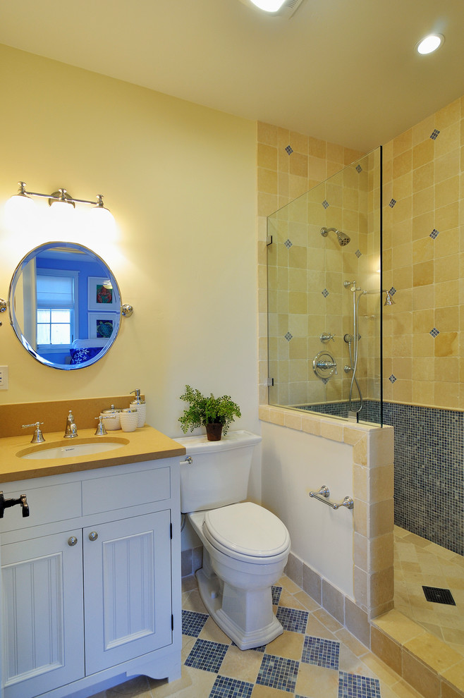 Foto på ett mellanstort amerikanskt badrum med dusch, med luckor med profilerade fronter, vita skåp, en öppen dusch, en toalettstol med separat cisternkåpa, beige kakel, blå kakel, porslinskakel, vita väggar, travertin golv, ett undermonterad handfat och bänkskiva i akrylsten