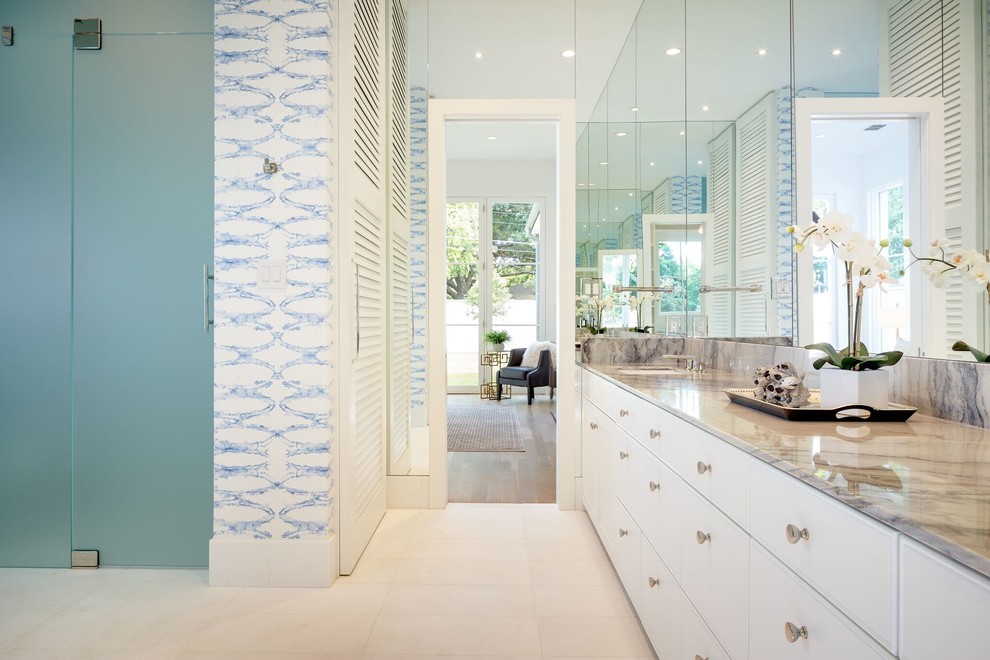 Cette image montre une grande salle de bain principale design avec un placard à porte plane, des portes de placard blanches, un sol en carrelage de porcelaine, un lavabo encastré et un plan de toilette en marbre.