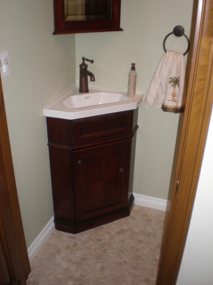Cette image montre une petite salle d'eau marine en bois foncé avec un lavabo intégré, un placard en trompe-l'oeil, un plan de toilette en surface solide, WC séparés, un mur vert et un sol en galet.