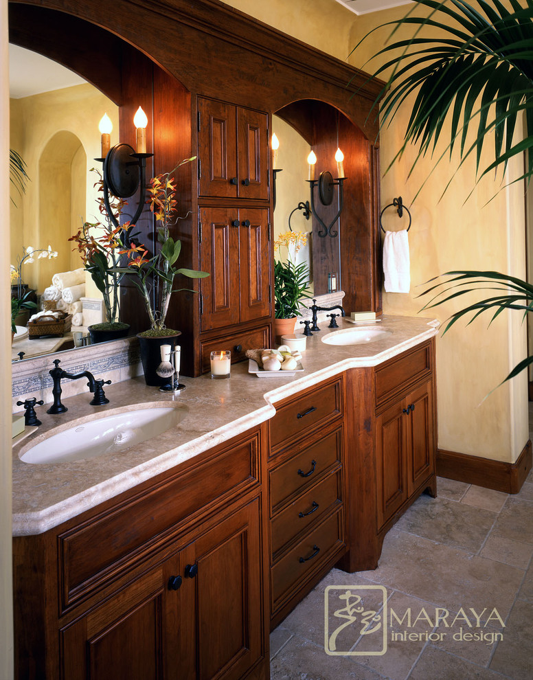 Идея дизайна: большая главная ванная комната в средиземноморском стиле с врезной раковиной, темными деревянными фасадами, накладной ванной, душем в нише, раздельным унитазом, бежевой плиткой, каменной плиткой, желтыми стенами, полом из известняка и фасадами с утопленной филенкой