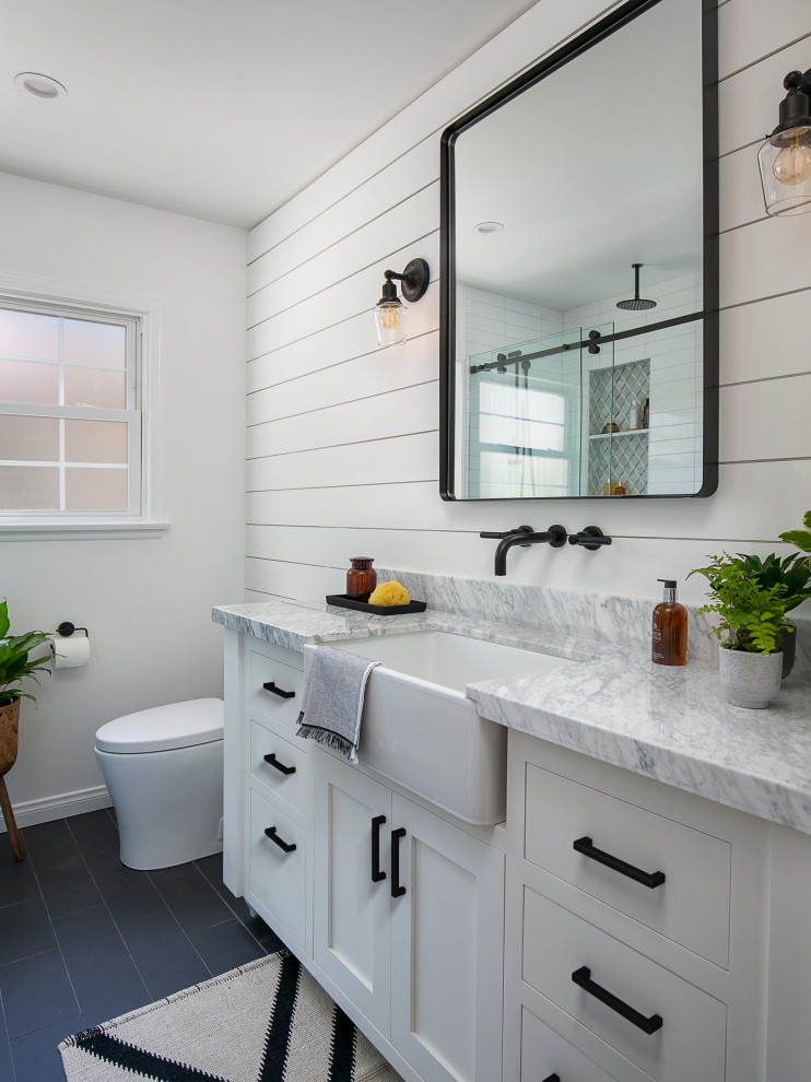 Photo of a small country shower room bathroom in Los Angeles with shaker cabinets, white cabinets, an alcove shower, a one-piece toilet, white tiles, porcelain tiles, white walls, porcelain flooring, a trough sink, marble worktops, grey floors, a sliding door and grey worktops.