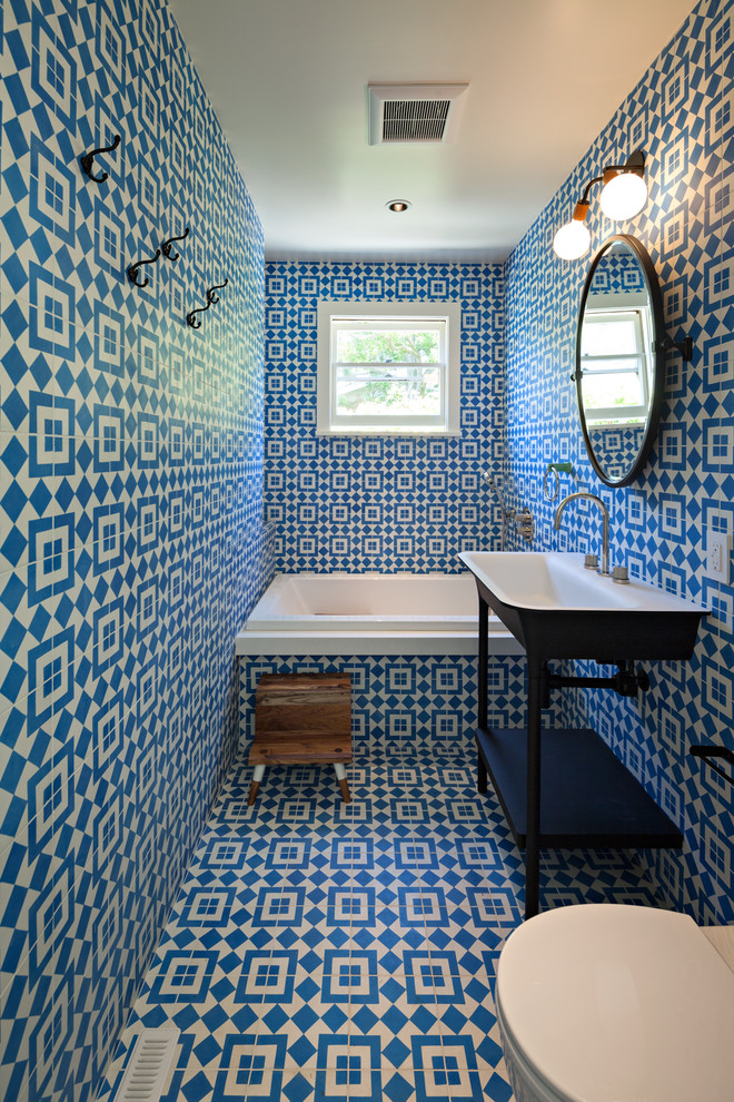 Foto de cuarto de baño ecléctico con bañera encastrada, sanitario de pared, paredes azules, lavabo suspendido y suelo azul