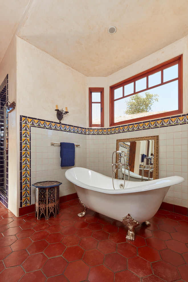 Imagen de cuarto de baño mediterráneo con bañera con patas, ducha empotrada, baldosas y/o azulejos blancos, paredes beige y suelo rojo