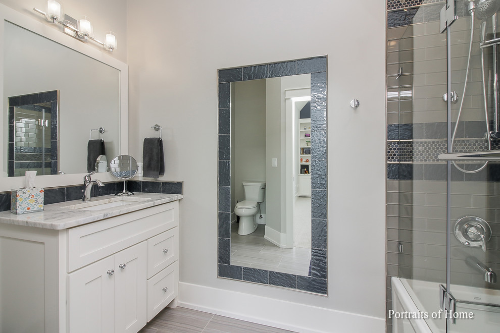 Inspiration for a medium sized contemporary family bathroom in Chicago with shaker cabinets, white cabinets, a built-in bath, a shower/bath combination, a one-piece toilet, grey tiles, mosaic tiles, grey walls, ceramic flooring, a submerged sink, granite worktops, grey floors, a hinged door and white worktops.