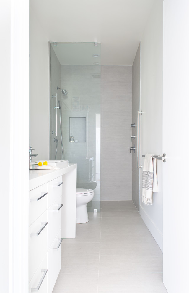 Modern inredning av ett mellanstort badrum med dusch, med släta luckor, vita skåp, en kantlös dusch, en toalettstol med hel cisternkåpa, grå kakel, keramikplattor, vita väggar, klinkergolv i keramik, ett nedsänkt handfat och bänkskiva i kvarts