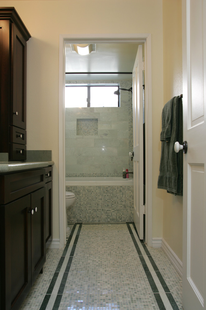 This is an example of a medium sized contemporary family bathroom in Los Angeles with shaker cabinets, dark wood cabinets, a built-in bath, a shower/bath combination, a two-piece toilet, green tiles, marble tiles, beige walls, marble flooring, a submerged sink, granite worktops, multi-coloured floors and a shower curtain.