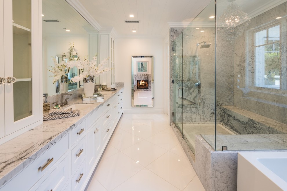 Inspiration for a contemporary grey and white ensuite bathroom in Los Angeles with recessed-panel cabinets, white cabinets, a freestanding bath, a corner shower, stone slabs and a submerged sink.