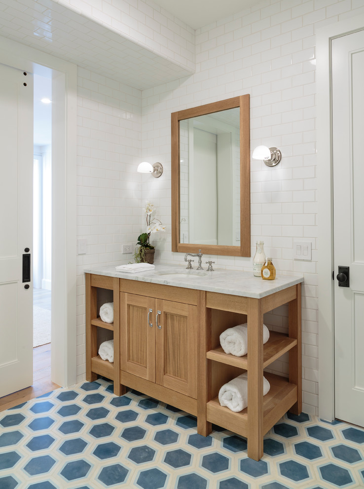 Ejemplo de cuarto de baño marinero con lavabo bajoencimera, puertas de armario de madera clara, baldosas y/o azulejos blancos, baldosas y/o azulejos de cemento y armarios con paneles empotrados