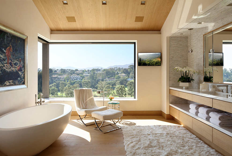 Idée de décoration pour une salle de bain principale design en bois clair avec une baignoire indépendante, un placard à porte plane, un mur beige, parquet clair et un plan de toilette beige.