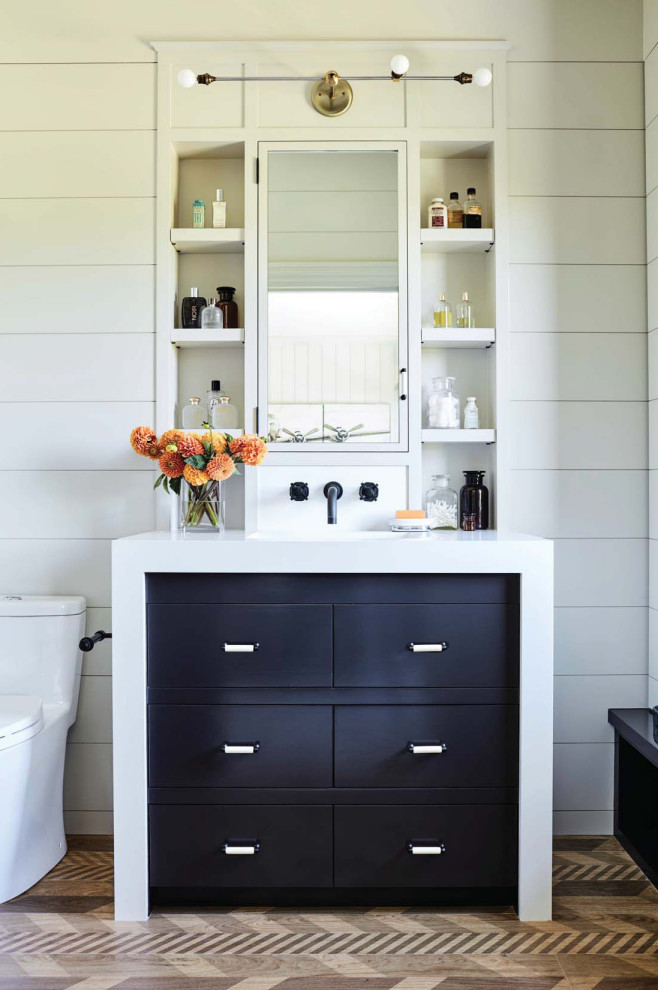 Example of a transitional dark wood floor, brown floor, single-sink and shiplap wall bathroom design in Los Angeles with flat-panel cabinets, black cabinets, a one-piece toilet, white walls, an undermount sink, white countertops and a built-in vanity