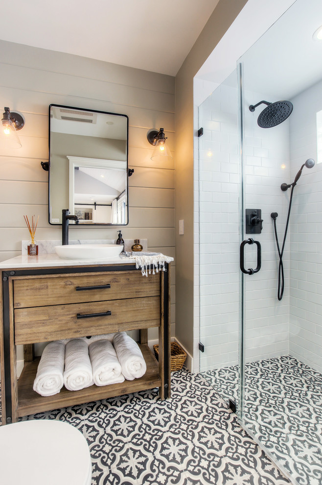 Aménagement d'une salle de bain campagne en bois brun avec un carrelage blanc, un carrelage métro, un mur gris, une vasque, un sol multicolore et un plan de toilette blanc.