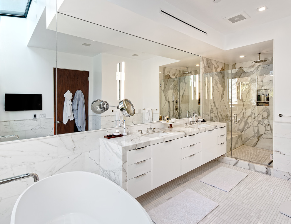 Idéer för att renovera ett stort funkis en-suite badrum, med släta luckor, vita skåp, ett fristående badkar, en dusch i en alkov, en toalettstol med hel cisternkåpa, vit kakel, marmorkakel, vita väggar, klinkergolv i porslin, ett undermonterad handfat, marmorbänkskiva, vitt golv och dusch med gångjärnsdörr