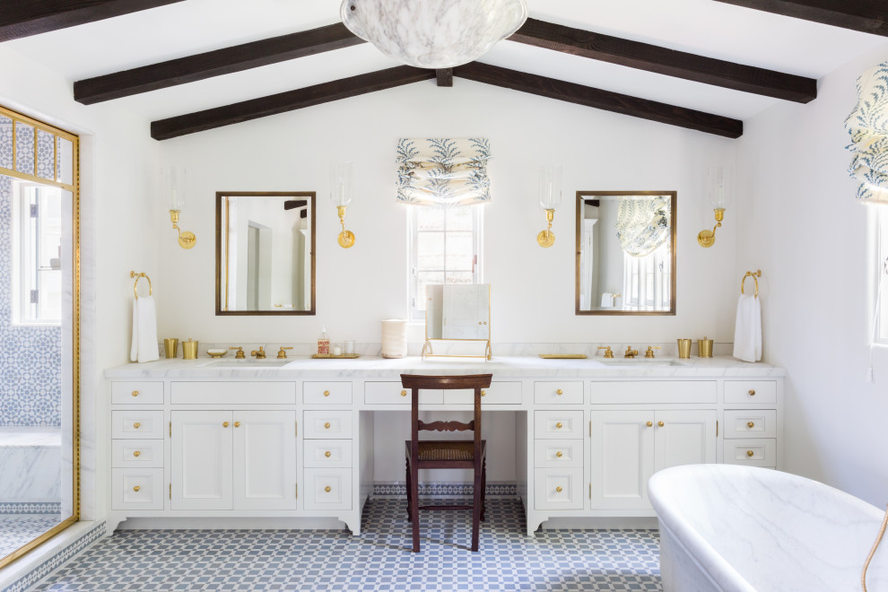 Inspiration for a medium sized mediterranean ensuite bathroom in Los Angeles with flat-panel cabinets, white cabinets, a freestanding bath, a one-piece toilet, blue tiles, cement tiles, white walls, ceramic flooring, a submerged sink, marble worktops, blue floors, white worktops, a shower bench, double sinks, a built in vanity unit and a vaulted ceiling.