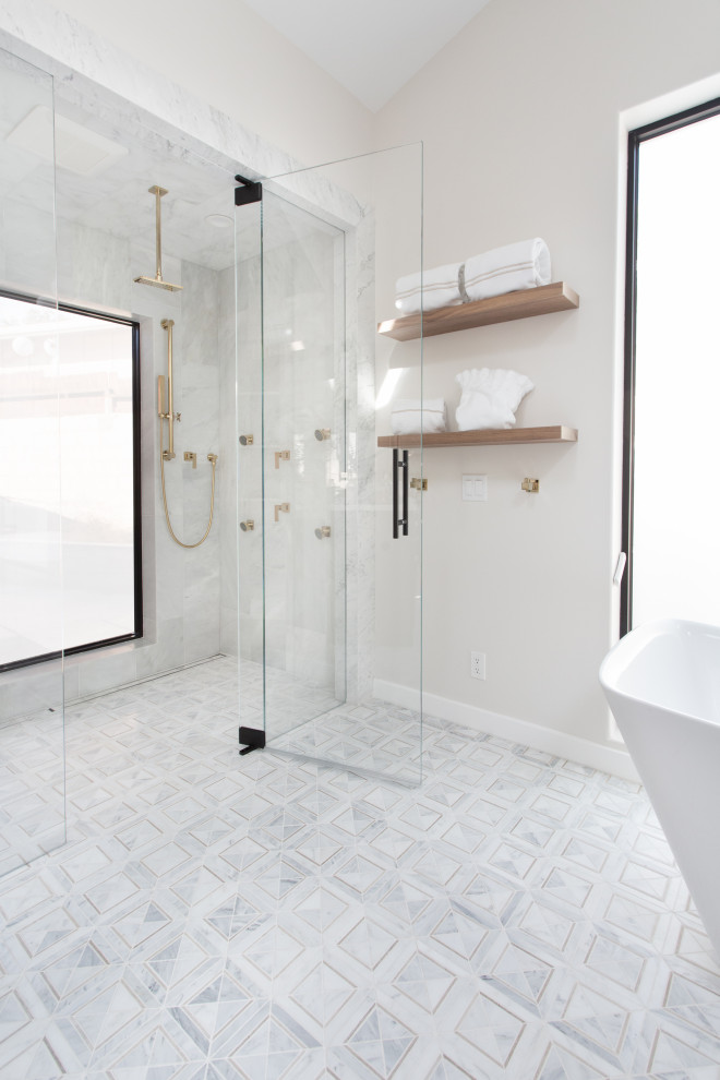 Стильный дизайн: огромная главная ванная комната в стиле неоклассика (современная классика) с отдельно стоящей ванной, душем в нише, белой плиткой, мраморной плиткой, белыми стенами, полом из мозаичной плитки, душем с распашными дверями и белым полом - последний тренд