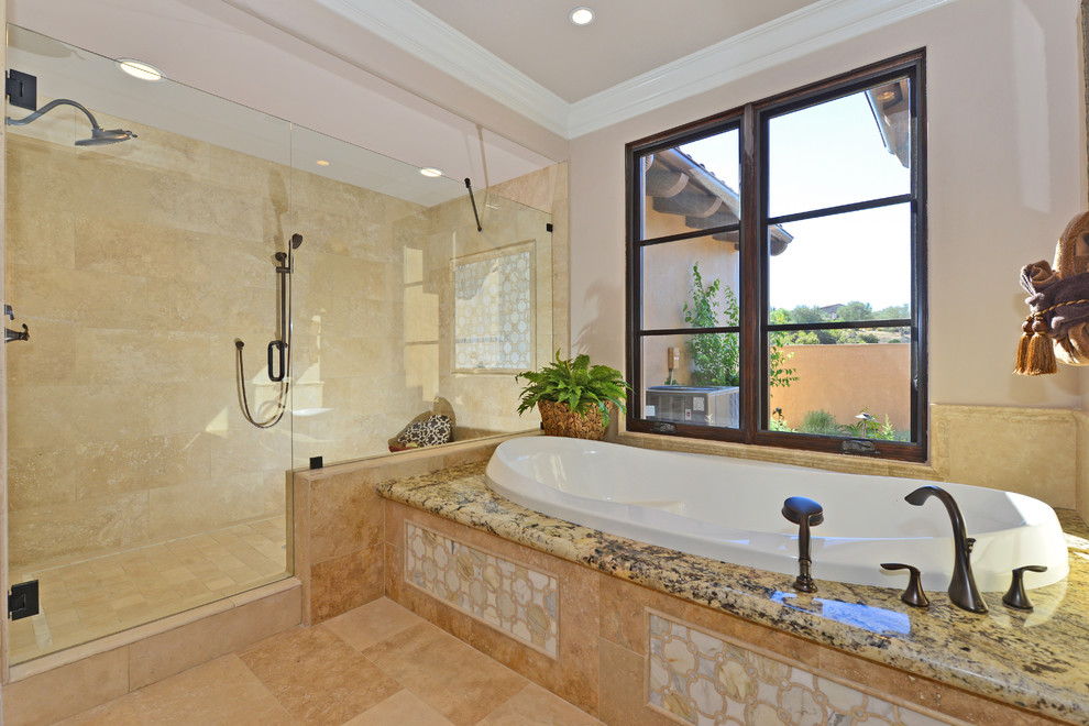 На фото: огромная главная ванная комната в средиземноморском стиле с фасадами с выступающей филенкой, фасадами цвета дерева среднего тона, столешницей из гранита, накладной ванной, двойным душем и полом из травертина