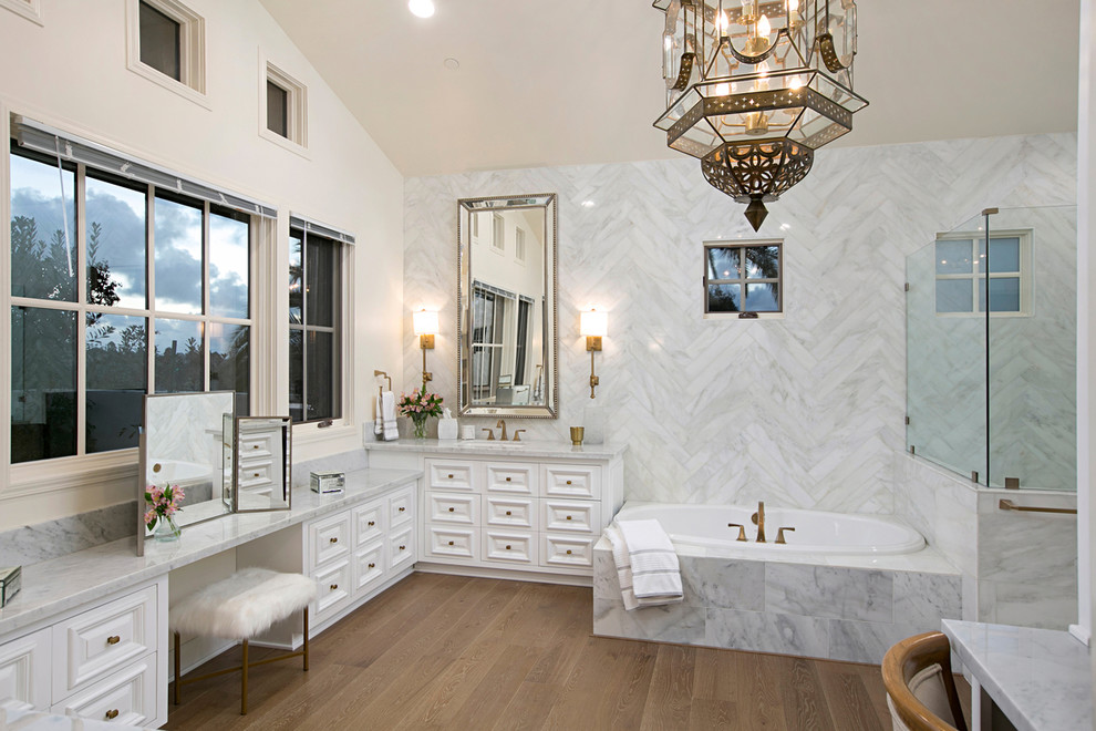 Idee per una stanza da bagno padronale mediterranea con consolle stile comò, ante bianche, vasca da incasso, doccia ad angolo, piastrelle di marmo, lavabo sottopiano e top in marmo