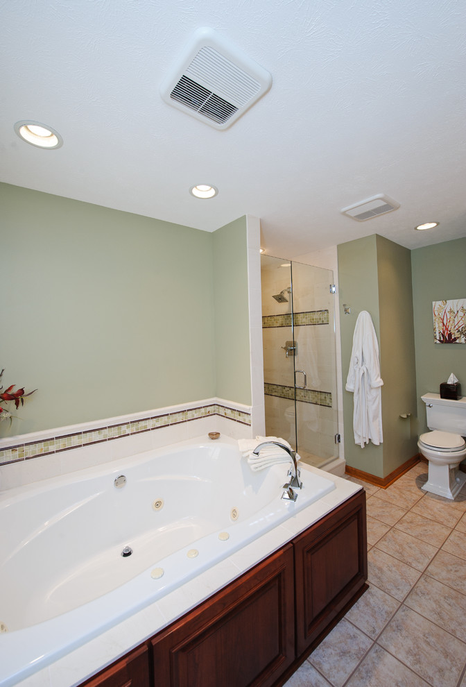 Klassisches Badezimmer mit dunklen Holzschränken, Eckbadewanne, Eckdusche, Toilette mit Aufsatzspülkasten und grüner Wandfarbe in Indianapolis