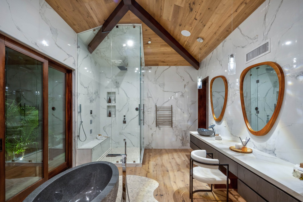 Источник вдохновения для домашнего уюта: ванная комната в современном стиле с плоскими фасадами, темными деревянными фасадами, отдельно стоящей ванной, угловым душем, белой плиткой, паркетным полом среднего тона, настольной раковиной, коричневым полом, душем с распашными дверями, белой столешницей, нишей, сиденьем для душа, подвесной тумбой, сводчатым потолком и деревянным потолком