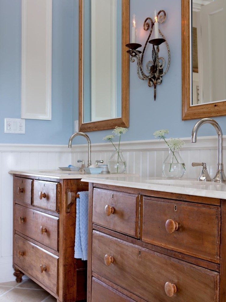 Imagen de cuarto de baño de estilo de casa de campo de tamaño medio con armarios tipo mueble, puertas de armario de madera oscura, paredes azules, suelo de piedra caliza y encimera de mármol