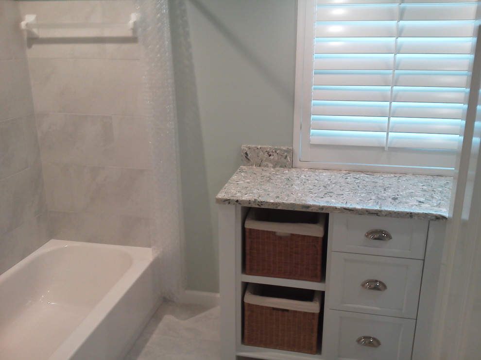 Photo of a medium sized classic bathroom in Tampa with white cabinets, glass worktops, a freestanding bath, a shower/bath combination, a two-piece toilet, porcelain tiles, green walls, porcelain flooring, recessed-panel cabinets, black and white tiles and a built-in sink.