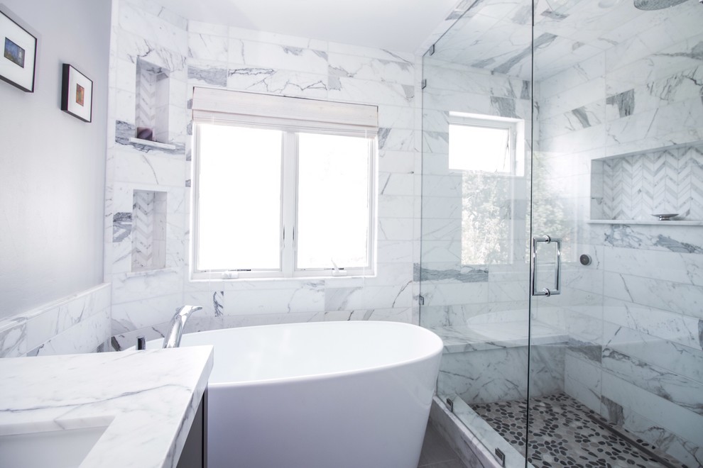 Exempel på ett mellanstort modernt vit vitt en-suite badrum, med släta luckor, svarta skåp, ett fristående badkar, våtrum, en toalettstol med hel cisternkåpa, vit kakel, stenkakel, grå väggar, klinkergolv i porslin, ett undermonterad handfat och marmorbänkskiva