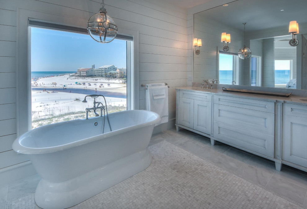 Cette photo montre une salle de bain principale bord de mer avec une baignoire indépendante, une douche ouverte, un carrelage beige et mosaïque.
