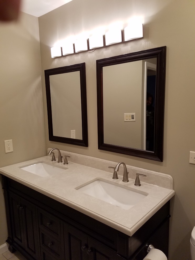 Example of a mid-sized classic kids' brown tile and ceramic tile ceramic tile bathroom design in DC Metro with recessed-panel cabinets, black cabinets, a one-piece toilet, beige walls, a wall-mount sink and granite countertops