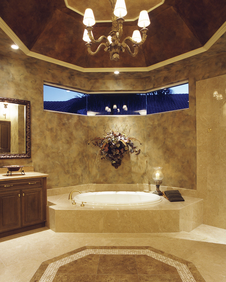 Cette image montre une très grande douche en alcôve principale méditerranéenne en bois foncé avec un placard avec porte à panneau surélevé, une baignoire posée, WC séparés, un carrelage beige, un carrelage de pierre, un mur beige, un sol en travertin, un lavabo encastré et un plan de toilette en quartz.