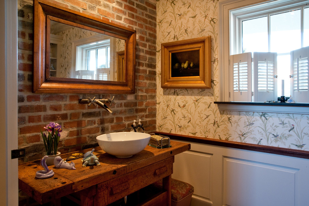 На фото: ванная комната в стиле кантри с фасадами островного типа, искусственно-состаренными фасадами, настольной раковиной и столешницей из дерева с