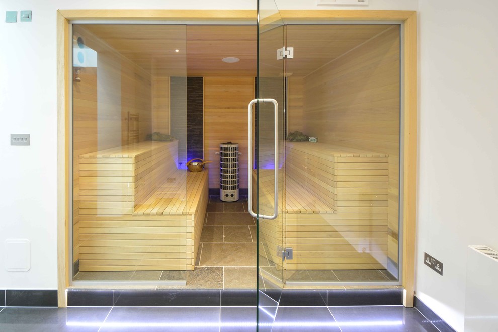Cette image montre un grand sauna design avec des dalles de pierre et un sol en calcaire.