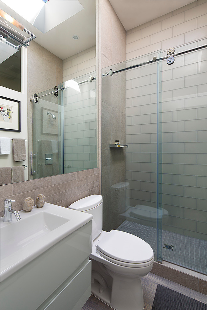 Foto på ett litet funkis badrum med dusch, med luckor med glaspanel, vita skåp, bänkskiva i kvarts, en dusch i en alkov, stenkakel, ett undermonterad handfat, en toalettstol med hel cisternkåpa och mellanmörkt trägolv