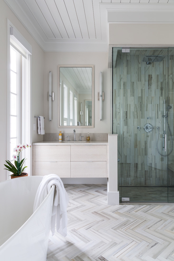 Foto di una stanza da bagno costiera con ante lisce, ante bianche, vasca freestanding, doccia ad angolo, pareti beige e piastrelle grigie
