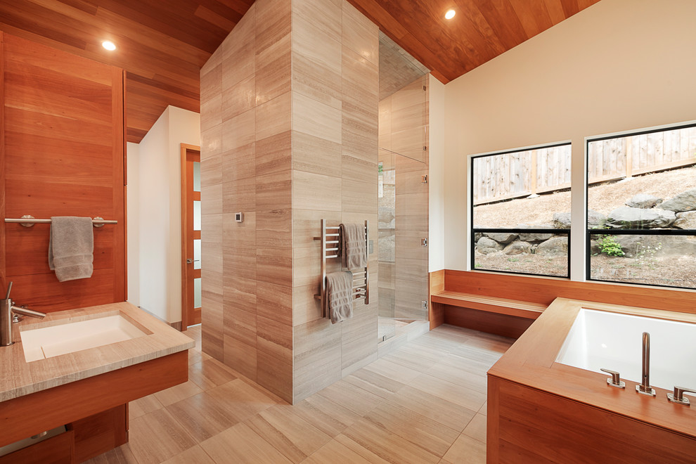 Aménagement d'une salle de bain principale contemporaine en bois brun avec une baignoire encastrée, un carrelage gris, un mur beige, un lavabo encastré, un sol gris et un plan de toilette beige.