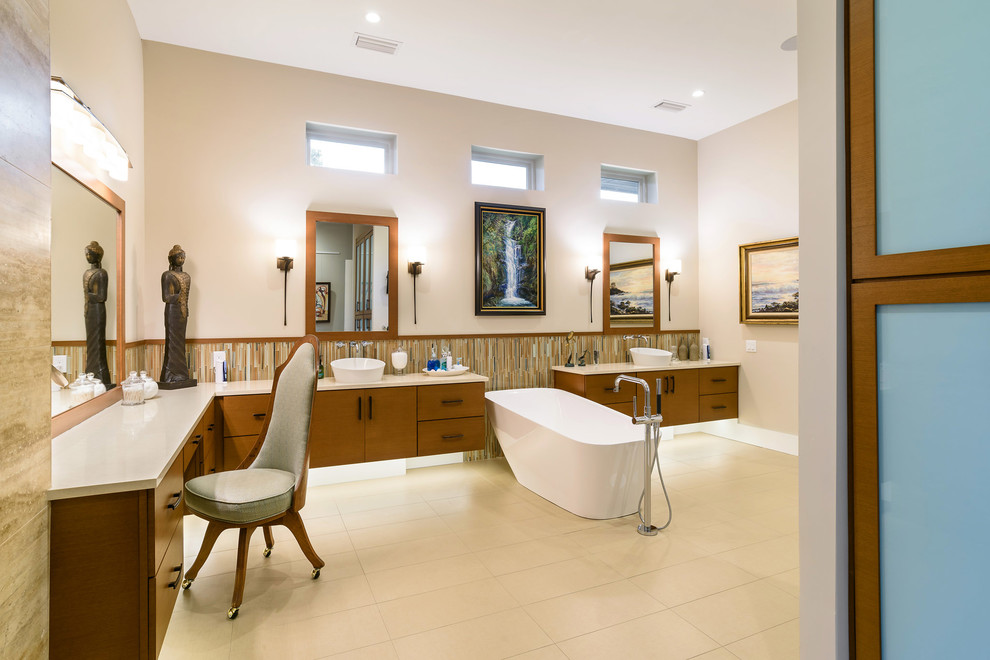 Источник вдохновения для домашнего уюта: главная ванная комната среднего размера в восточном стиле с плоскими фасадами, темными деревянными фасадами, отдельно стоящей ванной, разноцветной плиткой, удлиненной плиткой, бежевыми стенами, полом из керамогранита, настольной раковиной, столешницей из известняка, бежевым полом и бежевой столешницей