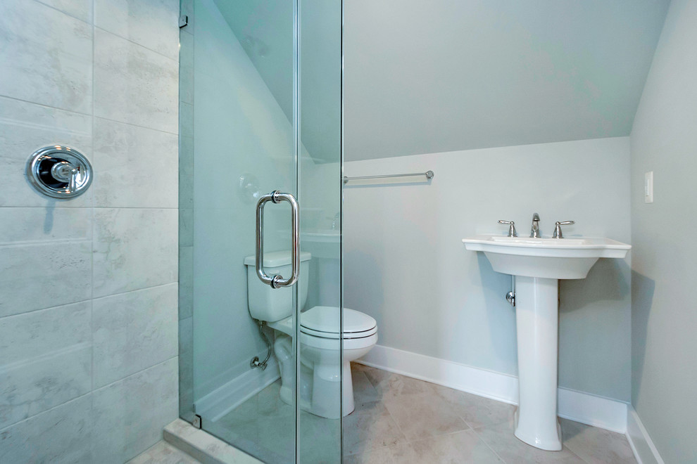 Bild på ett litet funkis badrum med dusch, med en hörndusch, en toalettstol med separat cisternkåpa, grå kakel, porslinskakel, klinkergolv i porslin, ett piedestal handfat, beiget golv, dusch med gångjärnsdörr och grå väggar