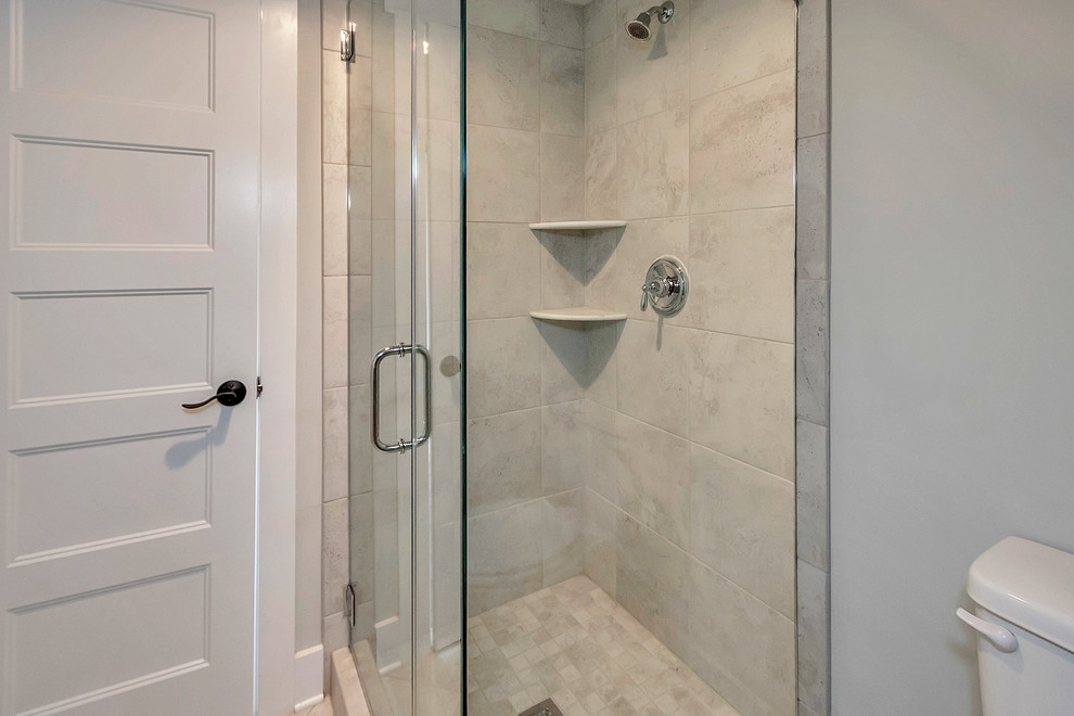 Foto på ett litet funkis badrum med dusch, med en hörndusch, en toalettstol med separat cisternkåpa, grå kakel, porslinskakel, klinkergolv i porslin, ett piedestal handfat, beiget golv, dusch med gångjärnsdörr och grå väggar